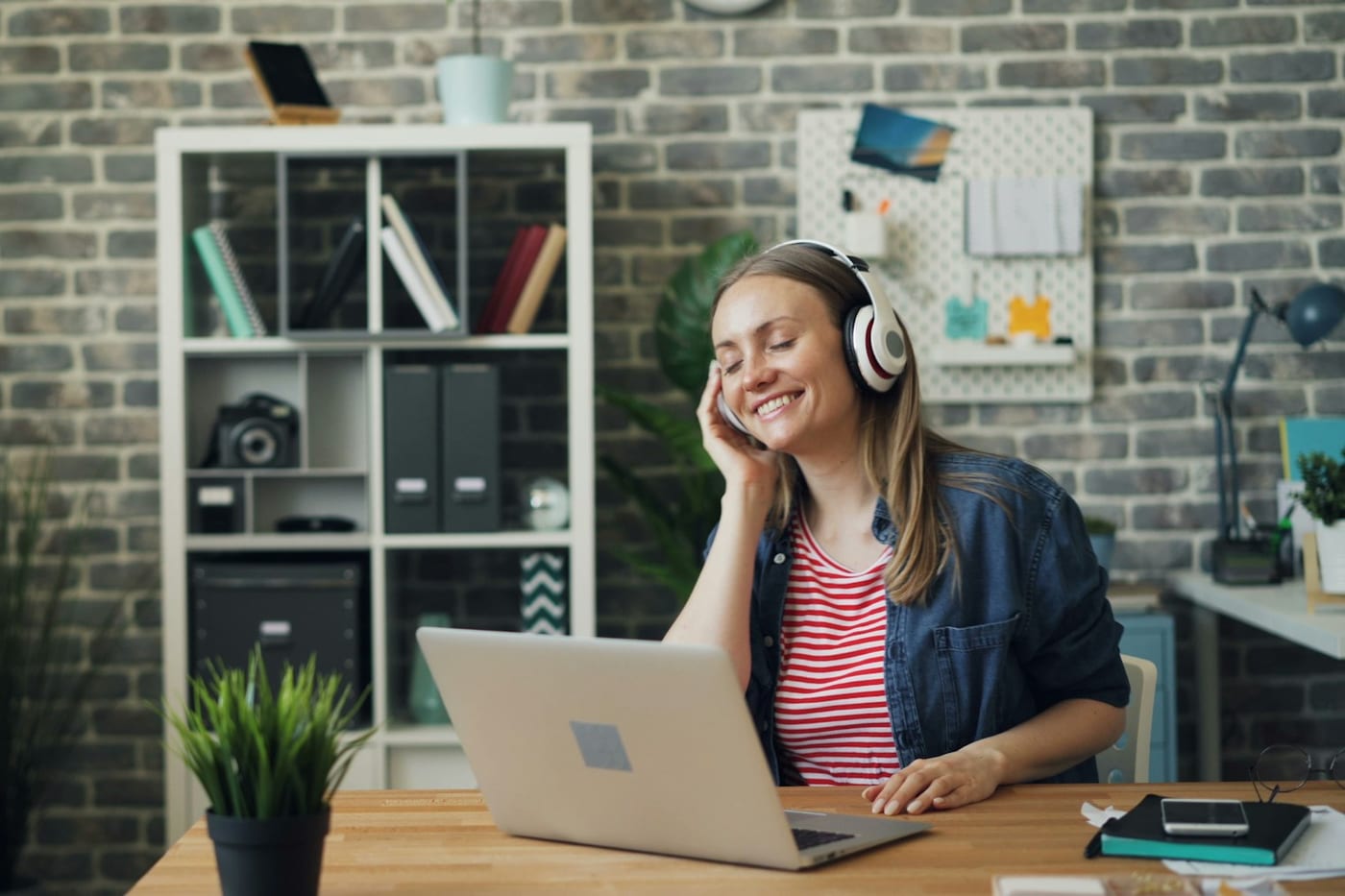 A remote team member working at a laptop with headphones on